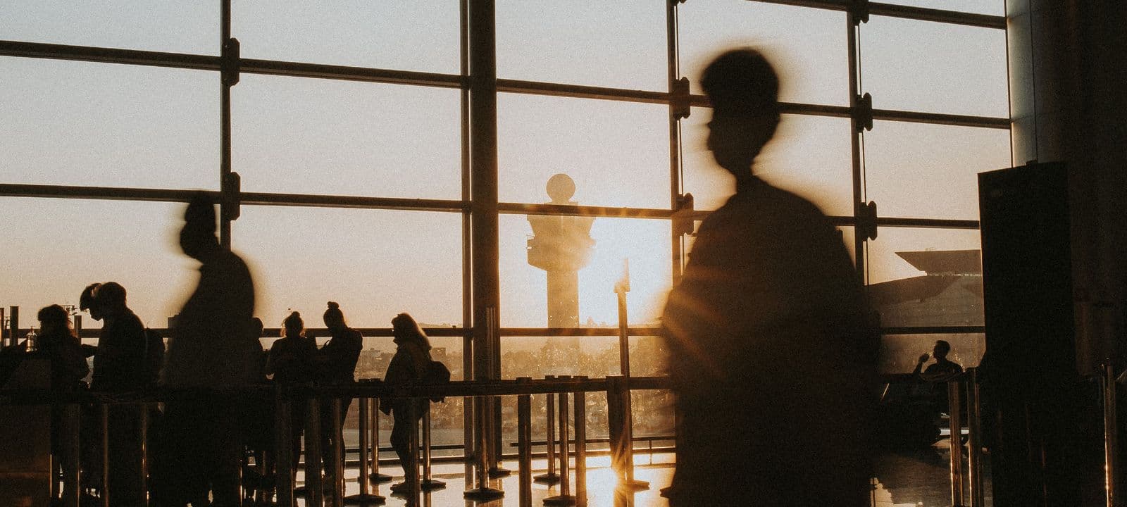 Travellers in silhouette in an airport terminal at sunset